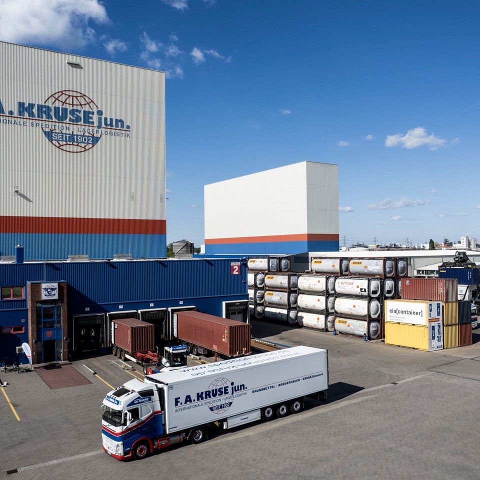 Logistikzentrum von F.A. Kruse jun. mit Hochregallagern, gestapelten Containern und Lkw auf dem Hof.